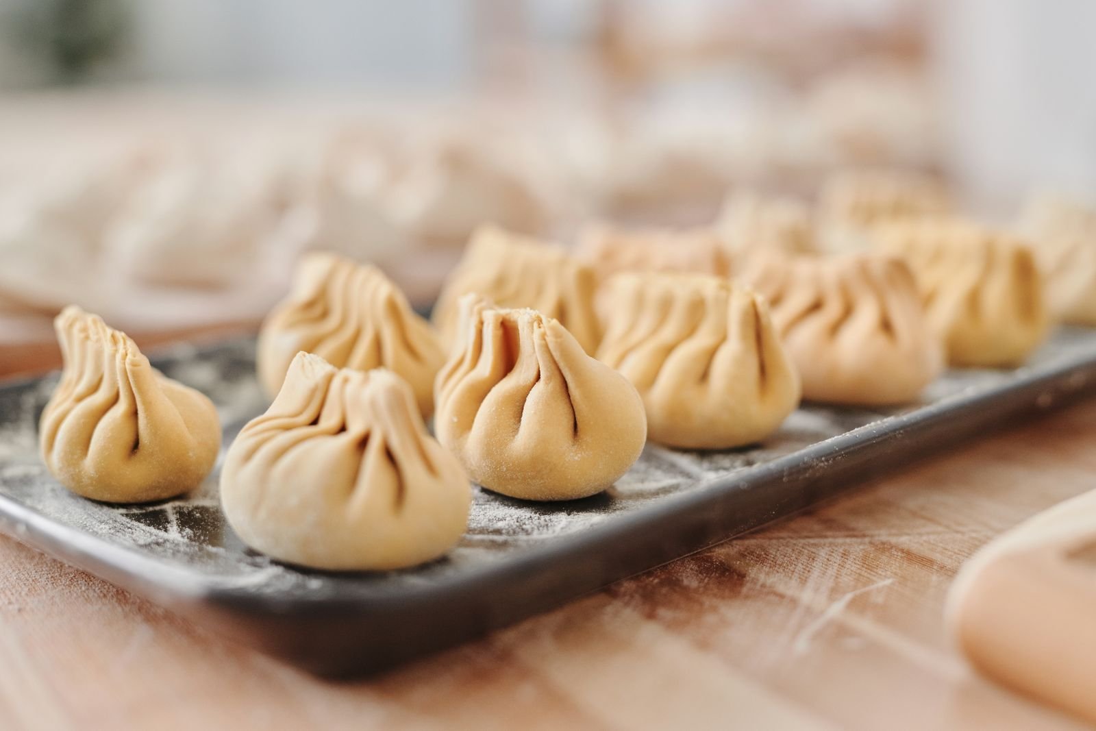 Uncooked handmade dumplings arranged on a floured tray