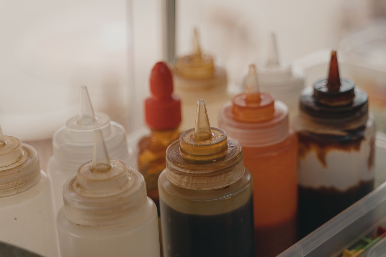 Unbranded condiment squeeze bottles organised for foodservice preparation